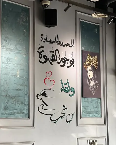 فنجان قهوة من لافا كافيه أمام جدارية عربية داخلية